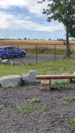 Dřevěná lavička a zaparkované auto na kraji vikingského parku ve Vendolí