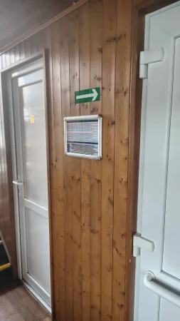 Dřevem obložená chodba na palubě lodi s informační tabulkou a WC.