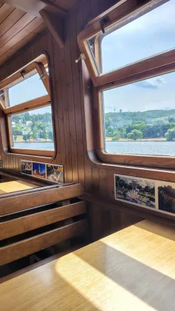 Dřevěná okna paluby s výhledem na jezero a fotografiemi na stěně.