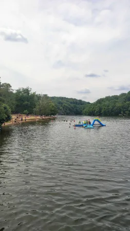 Lidé se koupou a užívají nafukovací skluzavku na pláži.