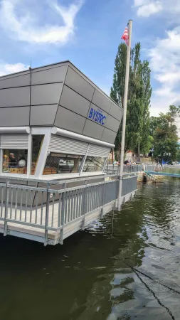 Moderní budova přístaviště Bystrc s vlajkou a molem na přehradě.