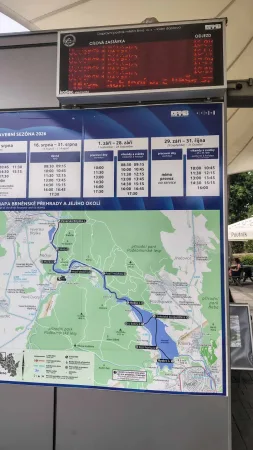 Elektronická odjezdová tabule s mapou Brněnské přehrady na zastávce lodi.