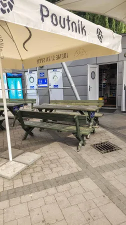 Venkovní posezení pod slunečníkem značky Poutník poblíž přístaviště Bystrc na přehradě.
