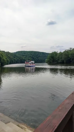 Výletní loď pluje mezi zalesněnými kopci u hradu Veveří.
