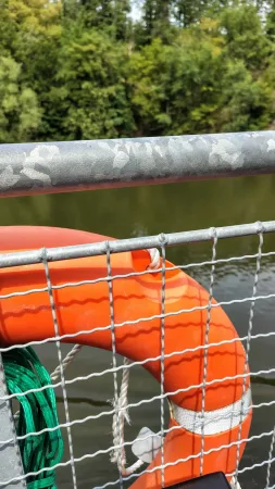 Oranžový záchranný kruh připevněný na kovovém zábradlí paluby výletní lodi.
