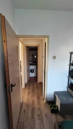 Chodba apartmánu s průhledem na pračku za otevřenými dveřmi