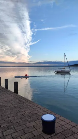 Kajak a plachetnice na dokonale klidné hladině Balatonu při soumraku