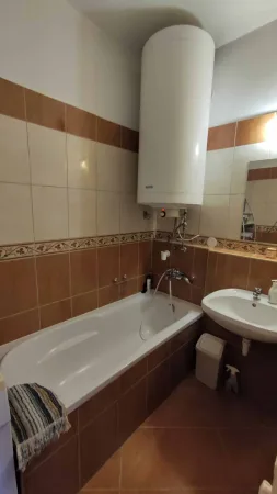Koupelna s vanou a bojlerem v béžovo-hnědém obkladu