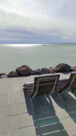 Lavičky s výhledem na průzračnou hladinu Balatonu za slunečného dne