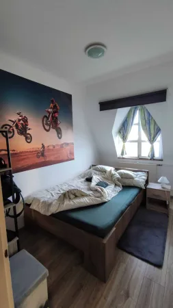 Ložnice s postelí a velkým plakátem motokrosu na zdi