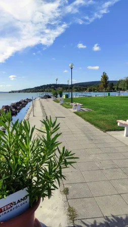 Dlážděná promenáda s lampami a výhledem na Balaton za slunečného dne