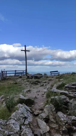 Croix en bois au sommet rocheux du Ještěd avec banc et panorama