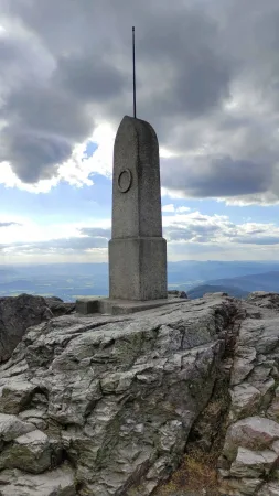 Borne de triangulation en pierre sur les rochers du sommet du Ještěd sous ciel nuageux