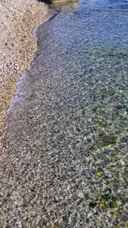 Průzračná voda a bílé oblázky na pláži Grčevo u Rijeky