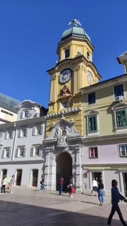 Žlutá městská věž s hodinami nad vstupní branou na korzu v Rijece