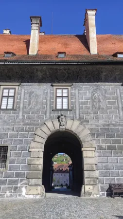 Kamenná brána zámku s výhledem na červené střechy Českého Krumlova