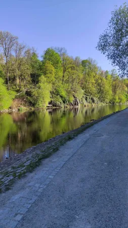 Klidná pěšina podél řeky Vltavy lemovaná zelenými stromy u Krumlova