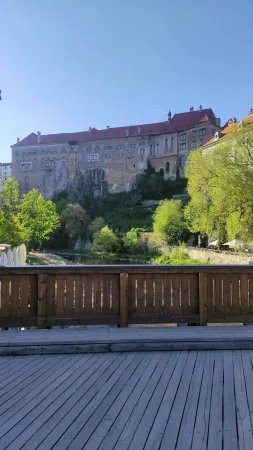 Dřevěný most přes řeku s večerním výhledem na zámek Český Krumlov