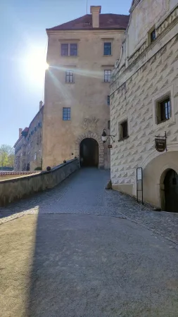 Sluncem prosvícený kamenný průchod vedoucí mezi nádvořími zámku v Českém Krumlově