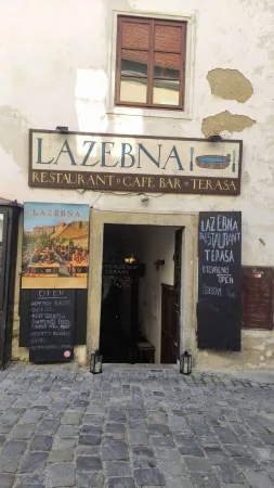 Vstup do restaurace Lazebna s dřevěnými cedulemi a jídelním lístkem