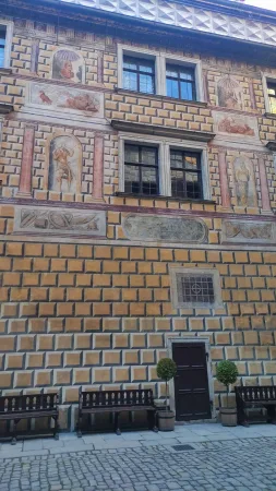 Detail malované fasády s lavičkami a stromky ve dvoře zámku Krumlov