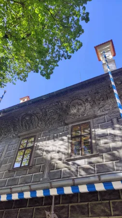 Zdobená renesanční římsa domu pod korunami stromů