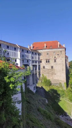 Zámecká budova s červenou střechou tyčící se na skále nad Českým Krumlovem