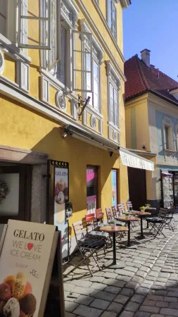 Žlutá zmrzlinárna se stolky na dlážděné uličce v Českém Krumlově