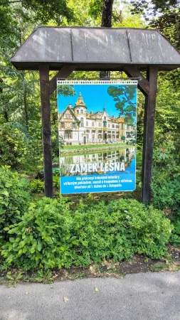 Ein Werbeschild für Schloss Lešná mit Foto und Text am Parkeingang