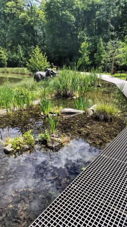 Ein Naturteich mit Schilf und einer Elefantenskulptur im Gelände des Zoos Lešná Zlín