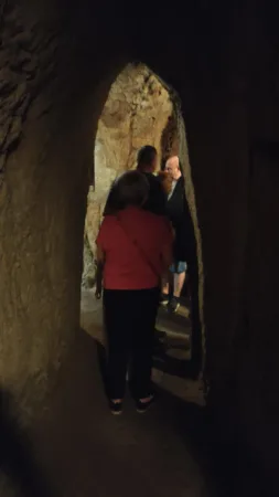 Návštěvníci procházejí úzkou klenutou chodbou uvnitř jeskyně