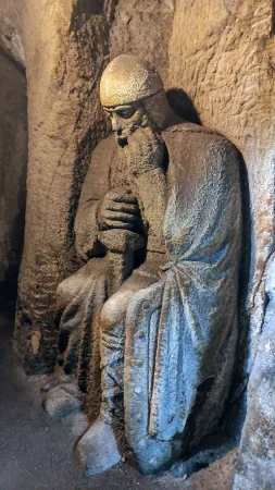 Detailně vytesaná kamenná postava v kápi ukrytá ve skalní nice