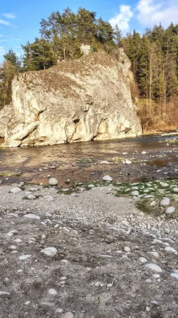 Un macizo rocoso junto a un río de montaña con cauce pedregoso y bosque