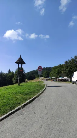 Cesta kolem Pusteven s dřevěným přístřeškem a dopravní značkou