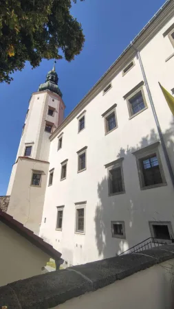 Detail zámecké věže v Hranicích s přilehlou bílou fasádou budovy