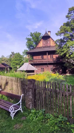 Dřevěná valašská chalupa s kvetoucí zahrádkou a dřevěným plotem
