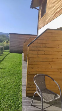 Ranní pohled na dřevěnou chatu s terasou a proutěnou židlí