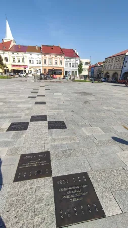 Pamětní desky v dlažbě s výhledem na historické domy náměstí