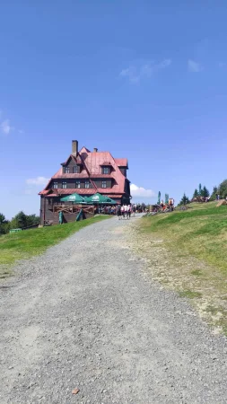 Horská chata s červenou střechou a terasou plnou turistů pod Radhoštěm