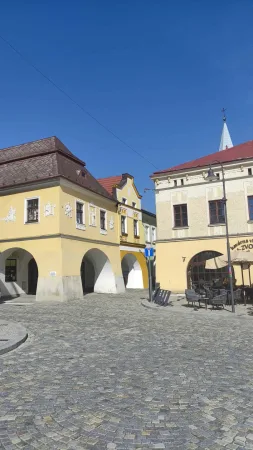 Žluté podloubí zdobené heraldickými reliéfy na náměstí ve Valašském Meziříčí