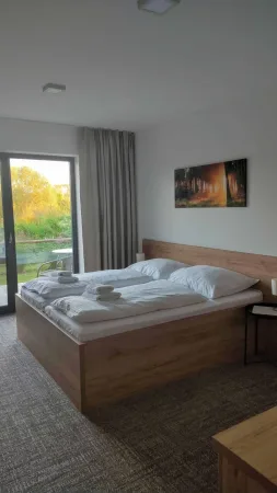 Útulný hotelový pokoj s manželskou postelí a výhledem na terasu