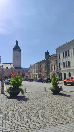 Radniční věž s hodinami tyčící se nad ulicí v centru Hranic