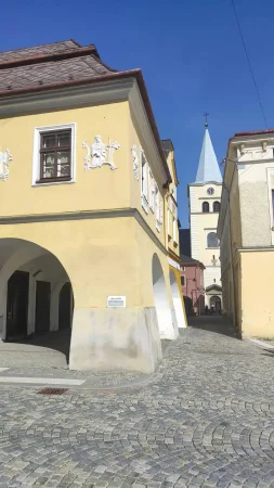 Úzká ulička s výhledem na věž kostela v historickém centru Valašského Meziříčí