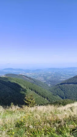 Výhled na beskydské údolí z hřebenové cesty pod jasnou oblohou