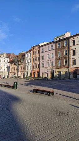 Barevné měšťanské domy na Malém rynku v Krakově, lavičky a modrá obloha nad dlažbou