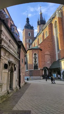 Věže Mariánského kostela v Krakově při pohledu z boční uličky pod klenutým průchodem za odpoledního světla