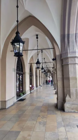 Klenuté podloubí tržnice Sukiennice v Krakově s litinovými lucernami a kamennou dlažbou