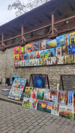 Pouliční galerie s barevnými obrazy zavěšenými na středověkých městských hradbách v Krakově