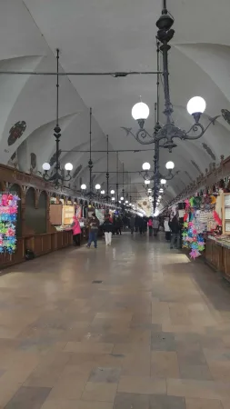 Klenutá vnitřní ulička tržnice Sukiennice v Krakově se stánky se suvenýry a litinovými lustry