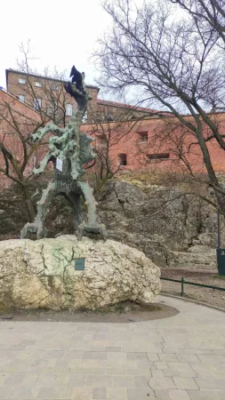 Socha Wawelského draka na velkém vápencovém balvanu pod hradbami hradu Wawel v Krakově